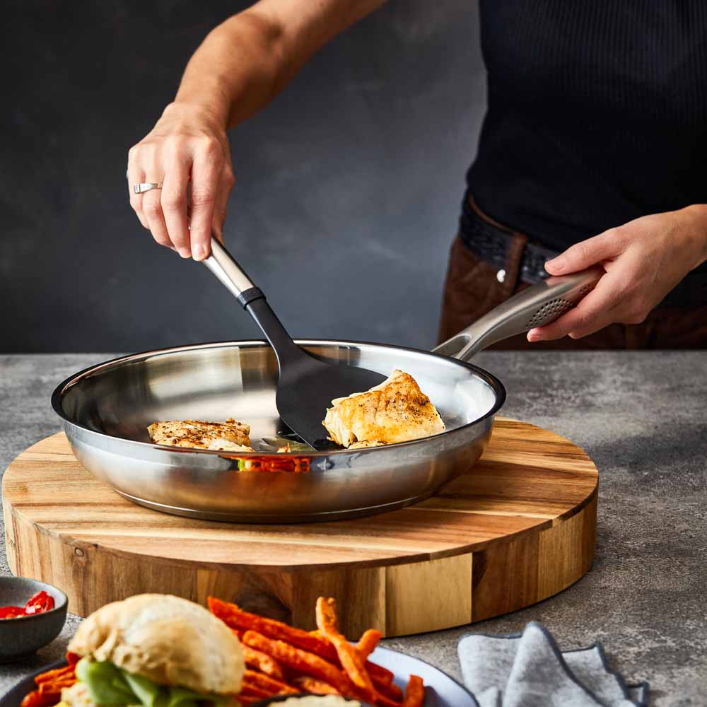 A stainless steel frying pan with a textured handle sits on a wooden board - frypan 26cm - Baccarat