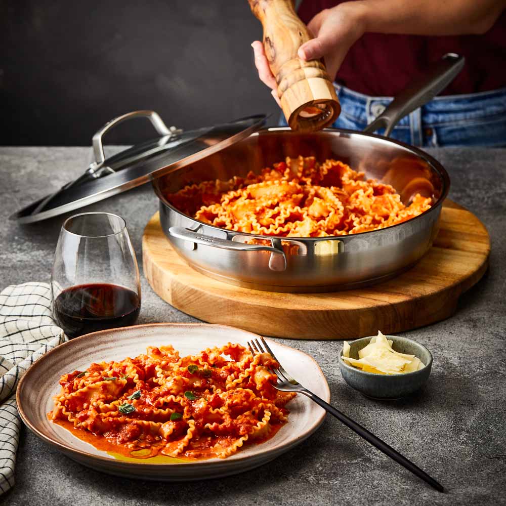 Five stainless steel cookware pieces with vegetables on a kitchen counter 24cm stockpot - Baccarat