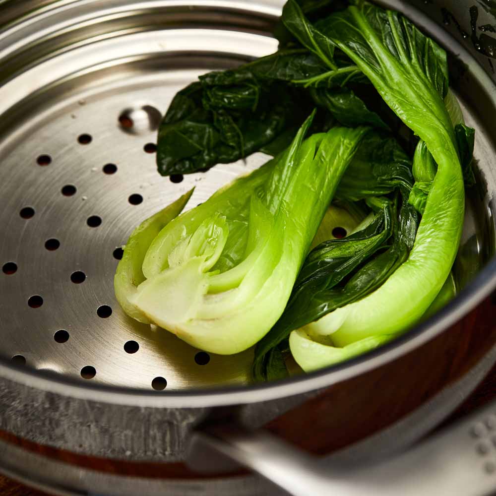 Five stainless steel cookware pieces with vegetables on a kitchen counter 24cm stockpot - Baccarat