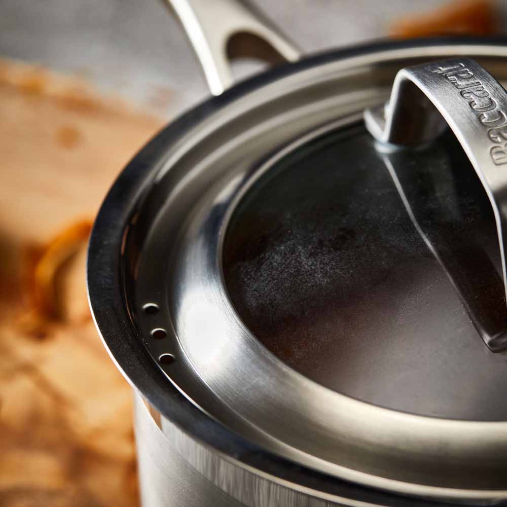 A stainless steel pot with a lid on wooden surface silver cookware 16cm saucepan with lid - Baccarat