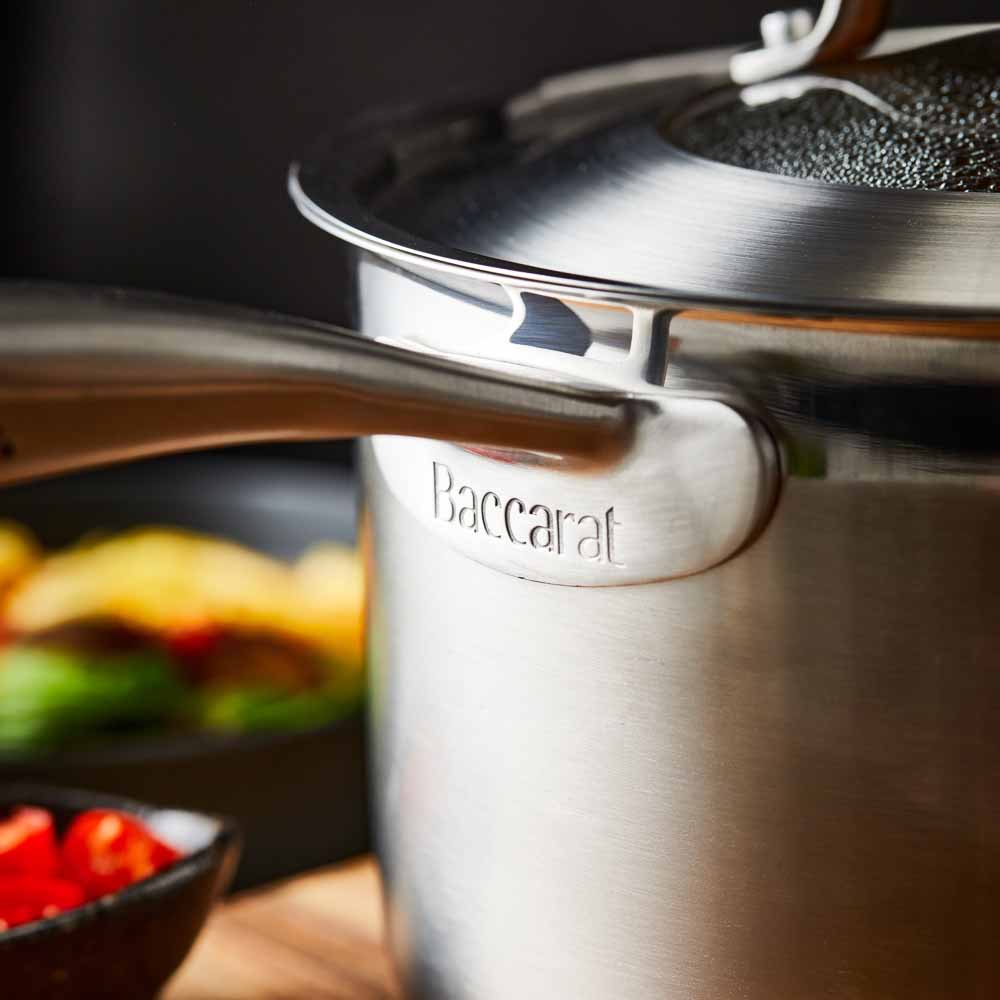 stainless steel saucepan 20cm pot of soup on a wooden board beside black bowl of noodles - Baccarat