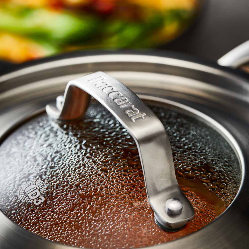 stainless steel saucepan 20cm pot of soup on a wooden board beside black bowl of noodles - Baccarat
