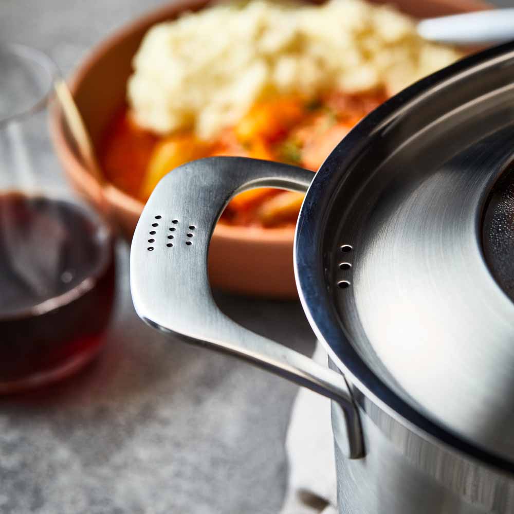 Five stainless steel cookware pieces with vegetables on a kitchen counter 24cm stockpot - Baccarat