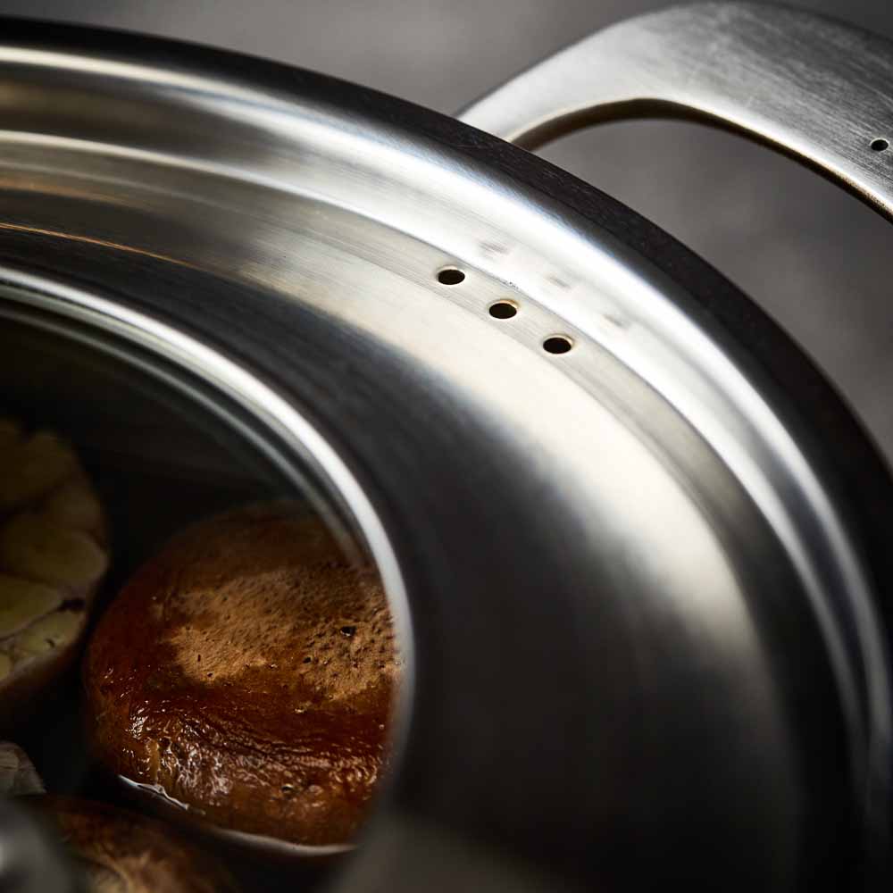 Close-up of a stainless steel pot lid with a handle and steam holes modern cookware 24cm - Baccarat