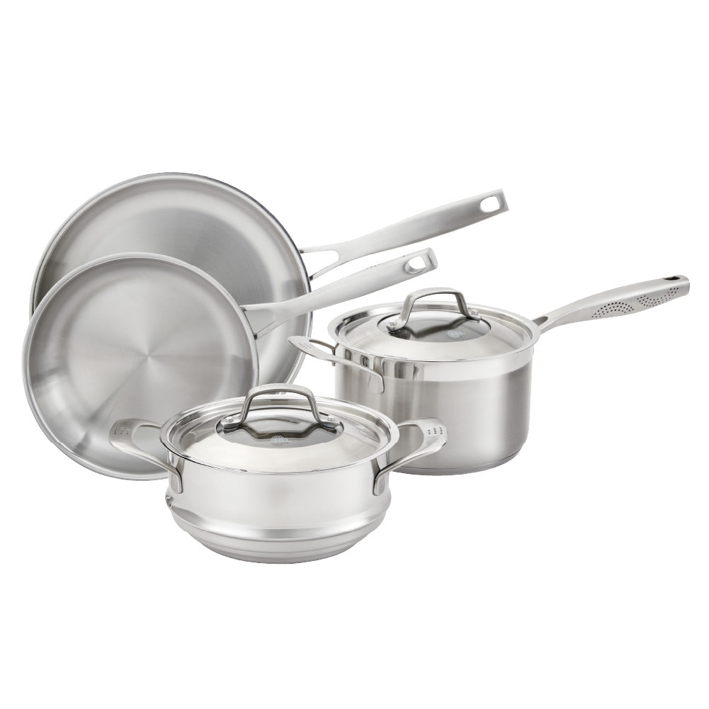 Four stainless steel cookware pieces on a gray surface including pots and pans with lid - Baccarat