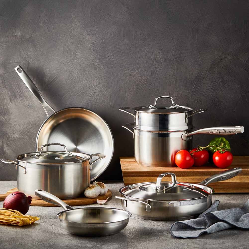 Five stainless steel cookware pieces with vegetables on a kitchen counter 24cm stockpot - Baccarat