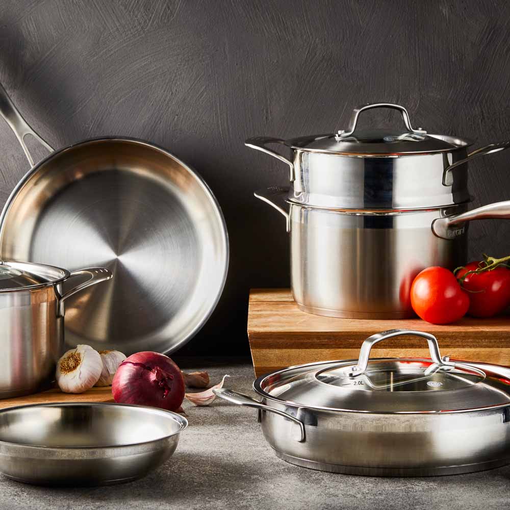 Five stainless steel cookware pieces with vegetables on a kitchen counter 24cm stockpot - Baccarat