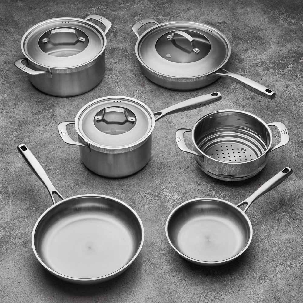 Five stainless steel cookware pieces with vegetables on a kitchen counter 24cm stockpot - Baccarat