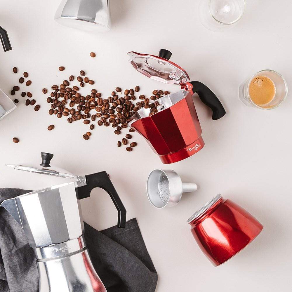 Coffee beans spilling from a red espresso maker on a white surface - Baccarat barista italico