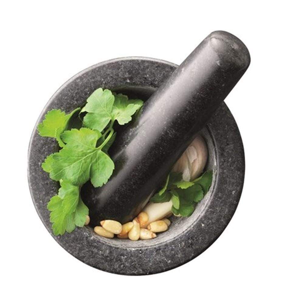 Top view of a dark gray mortar and pestle with fresh herbs and nuts - Baccarat spice market gino