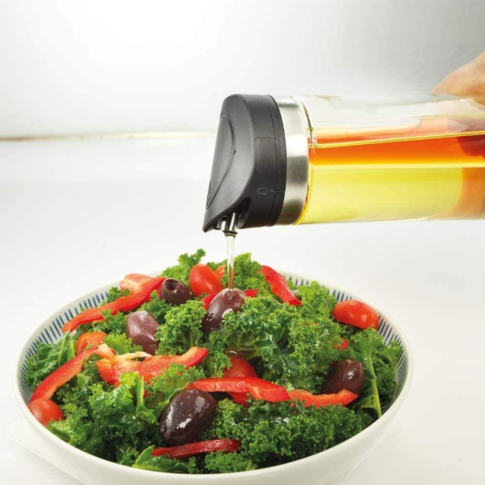 Pouring rich olive oil onto a vibrant kale salad with olives - Baccarat spice market oil and vinegar