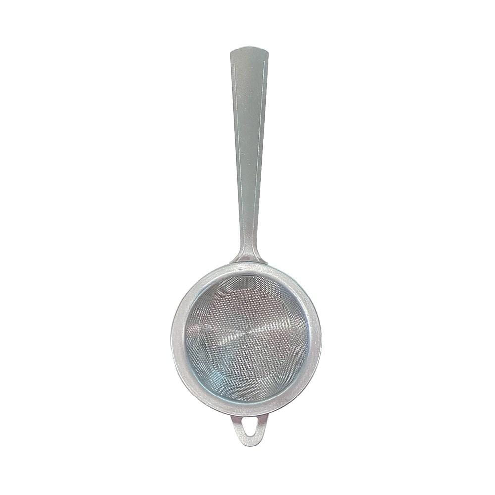 A stainless steel tea strainer with a handle beside a stylish bowl - Baccarat tea house