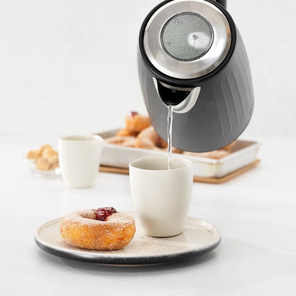 Black kettle pours hot water into a white cup beside a pastry plate - Baccarat Boiling Point Kettle