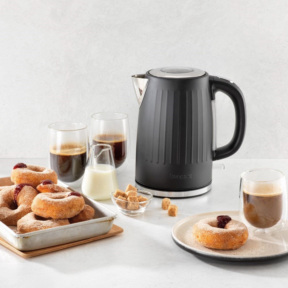 Black kettle pours hot water into a white cup beside a pastry plate - Baccarat Boiling Point Kettle