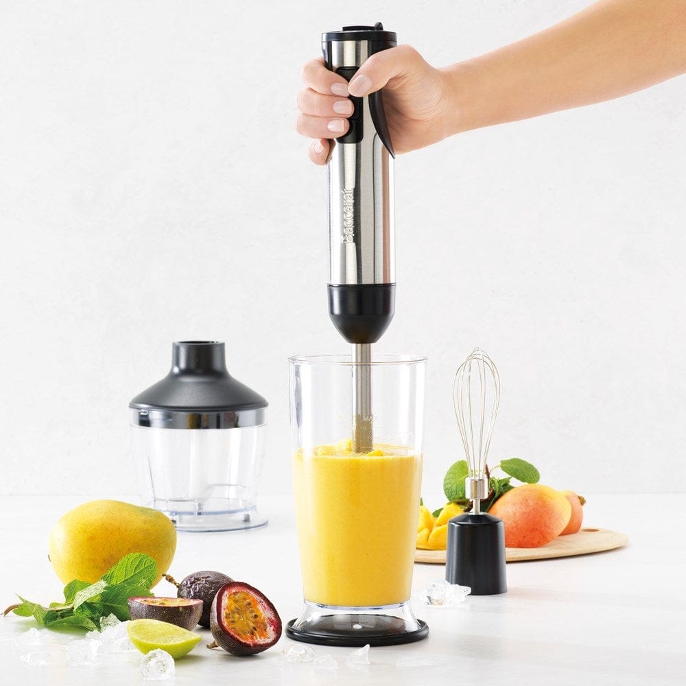 A yellow smoothie is blended surrounded by fresh fruits with a Baccarat The Quick Mix Stick Blender