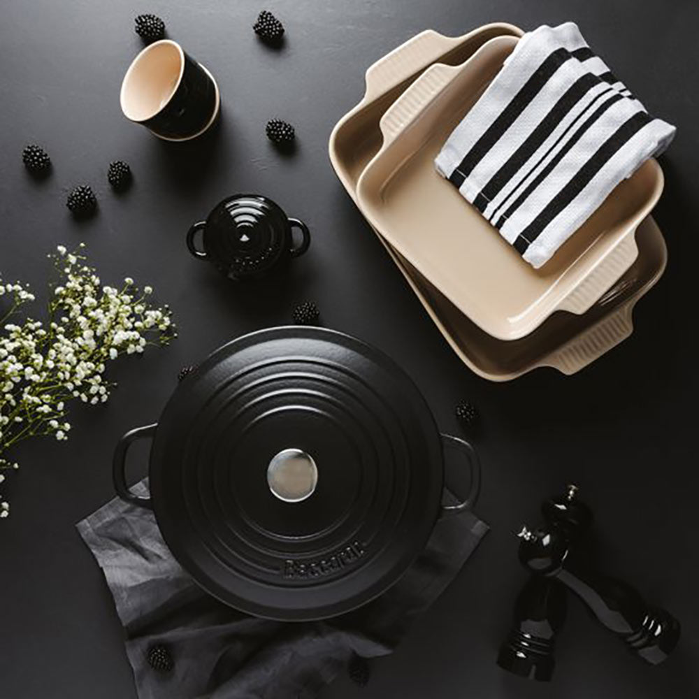 A black cast iron pot on a dark surface with a beige dish and striped towels 300ml red - Baccarat