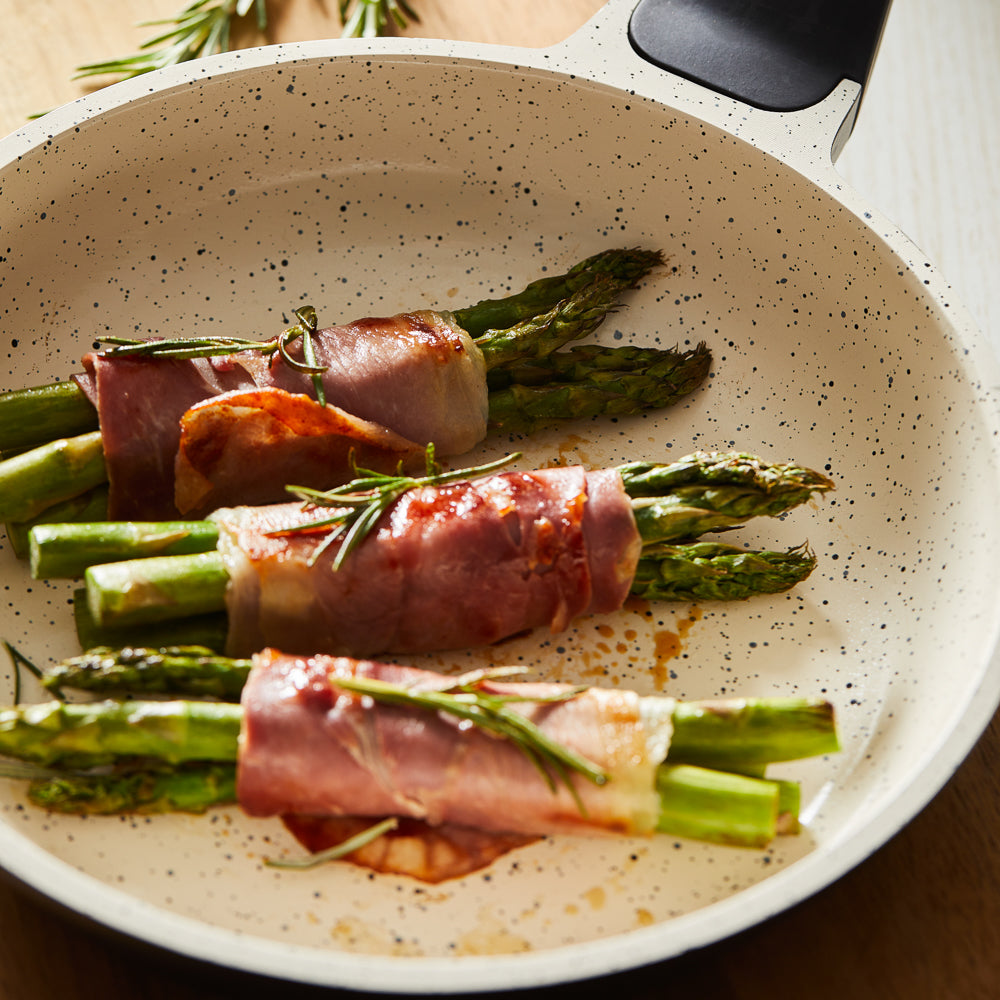 Three bundles of asparagus wrapped in prosciutto in a white fry pan - Baccarat ceramix fry pan 20cm