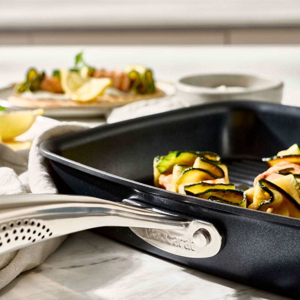 A close-up view shows the handle attachment and edge of a black grill pan.