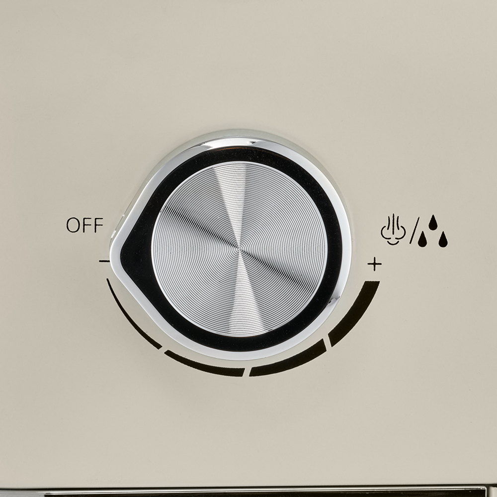A close-up view focuses on the silver control dial on the side of a cream espresso machine.