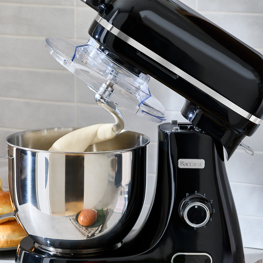 Black stand mixer with a silver bowl and dough attachment on a kitchen counter.