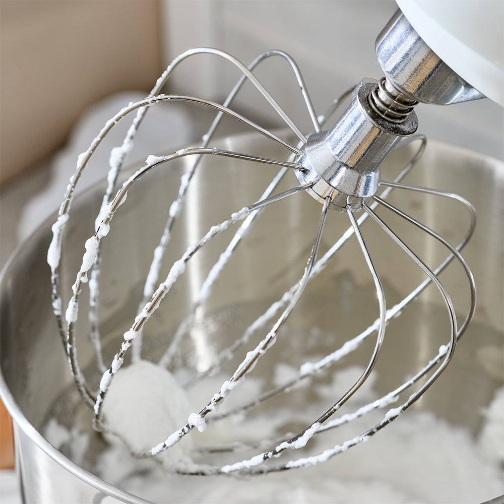Kitchen mixer whisk attachment with whipped cream in a bowl
