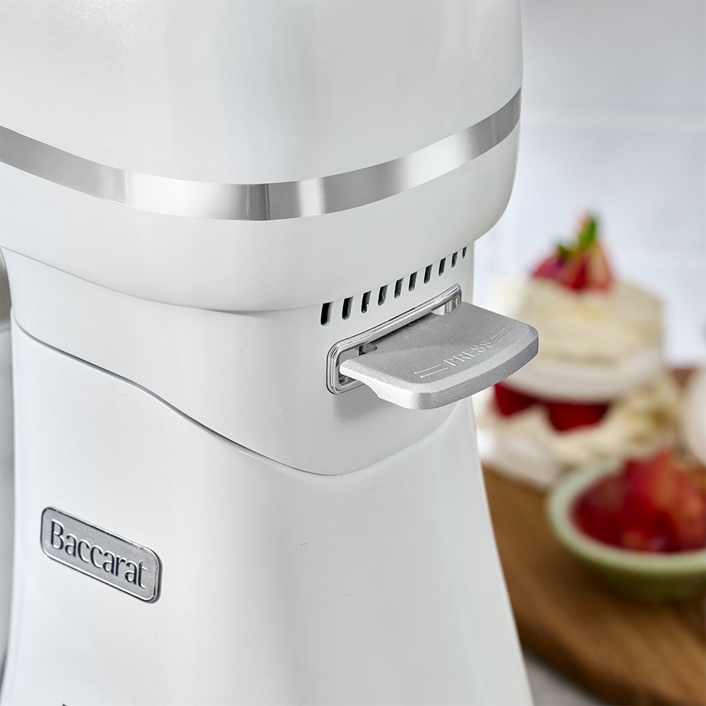 White kitchen appliance with 'Baccarat' branding, blurred dessert in the background