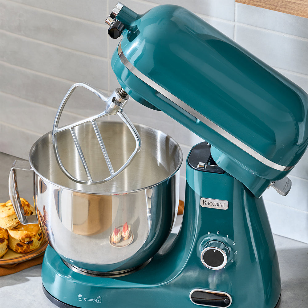 Turquoise stand mixer with a silver mixing bowl on a kitchen counter.