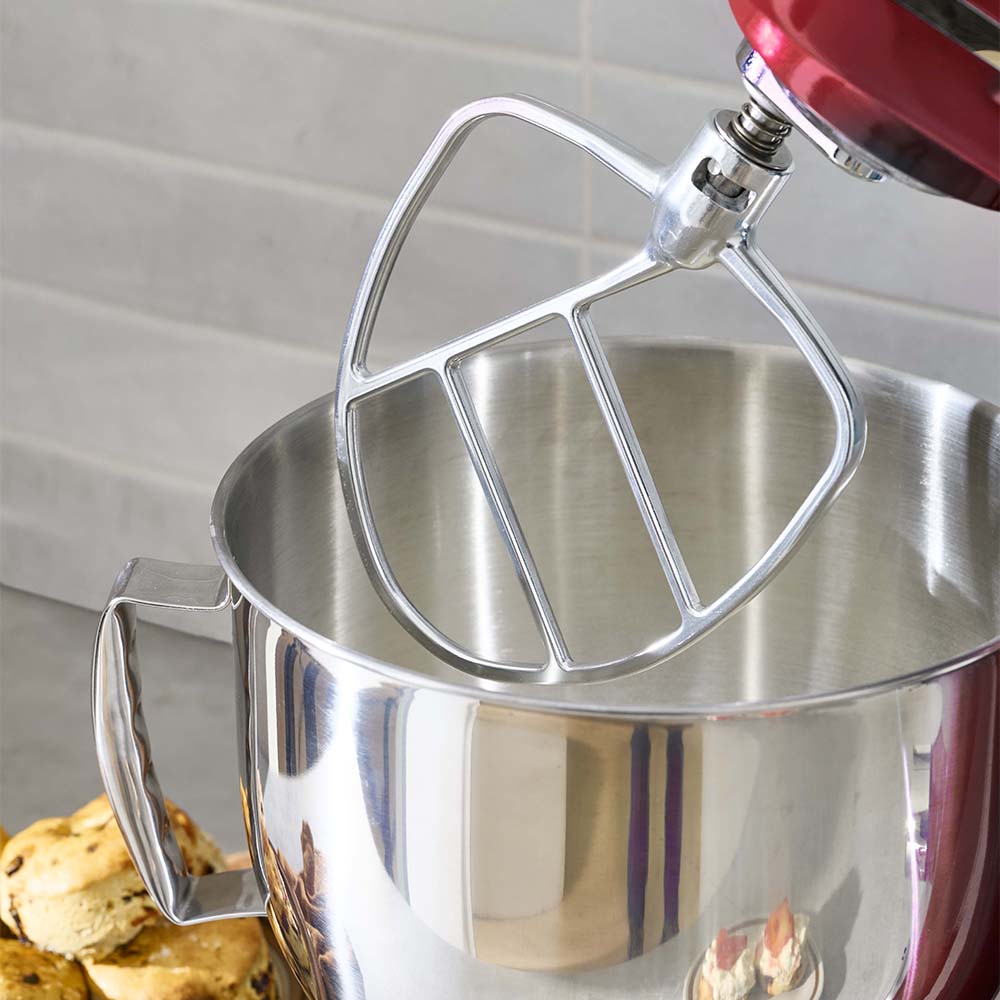 Metal mixing bowl with stand mixer attachment on a kitchen counter
