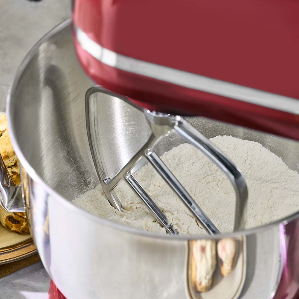 Red stand mixer with a metal bowl containing flour
