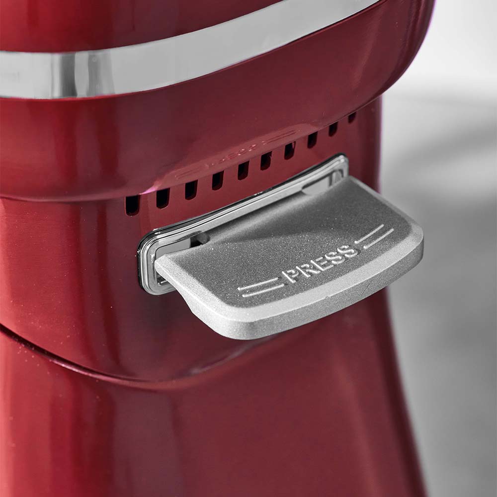 Red kitchen appliance with a silver 'PRESS' lid on a gray background