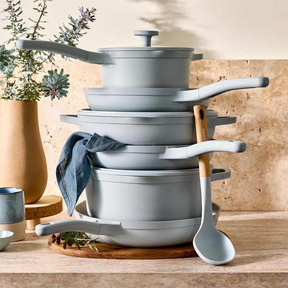 A neat stack of light blue cookware pieces is arranged on a wooden countertop.