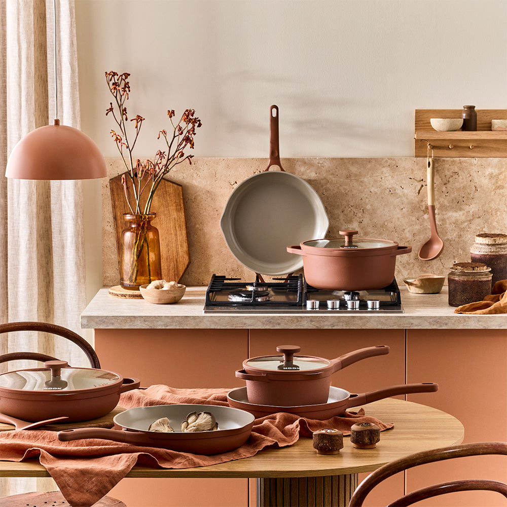 kitchen table and countertop setup is arranged with terracotta-colored pots, pans, and matching utensils.