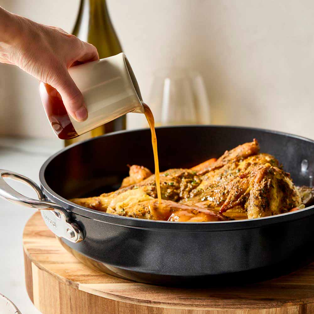 Roasted chicken with vegetables in a black frypan on a wooden board black frypan 28cm - Baccarat