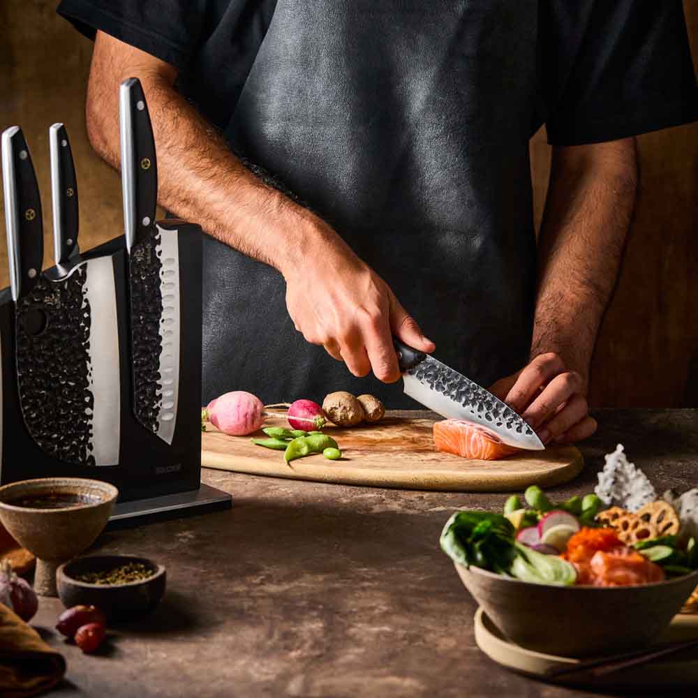 Man slicing salmon with Baccarat KUROI KIBA 7 Piece Knife Block at Baccarat