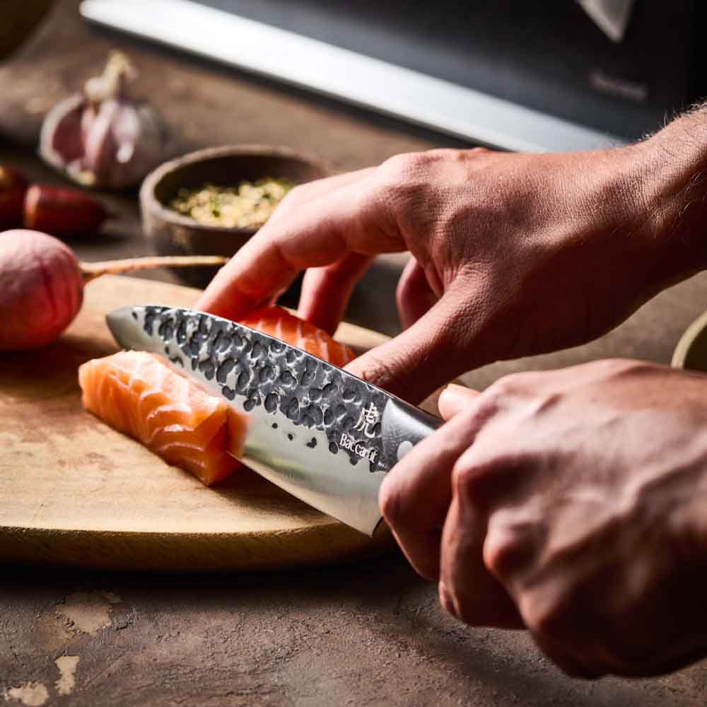 Man slicing salmon with Baccarat KUROI KIBA 7 Piece Knife Block at Baccarat