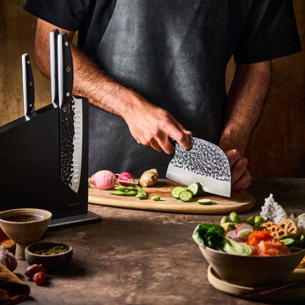 Man slicing cucumber with Baccarat KUROI KIBA 7 Piece Knife Block at Baccarat