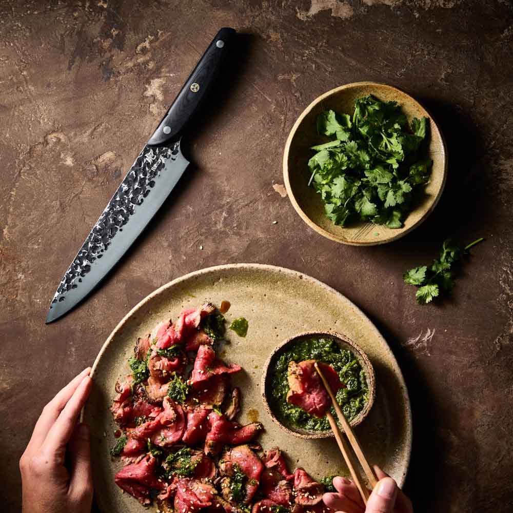 Man dipping sliced wagyu beef - Baccarat KUROI KIBA Chefs Knife 20cm at Baccarat