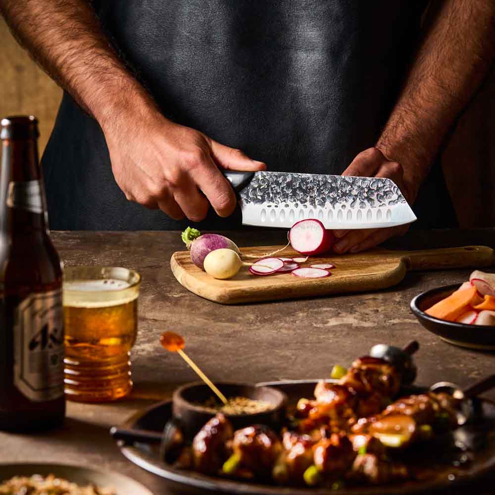 Man slicing radish with Baccarat KUROI KIBA Santoku Knife 18cm at Baccarat