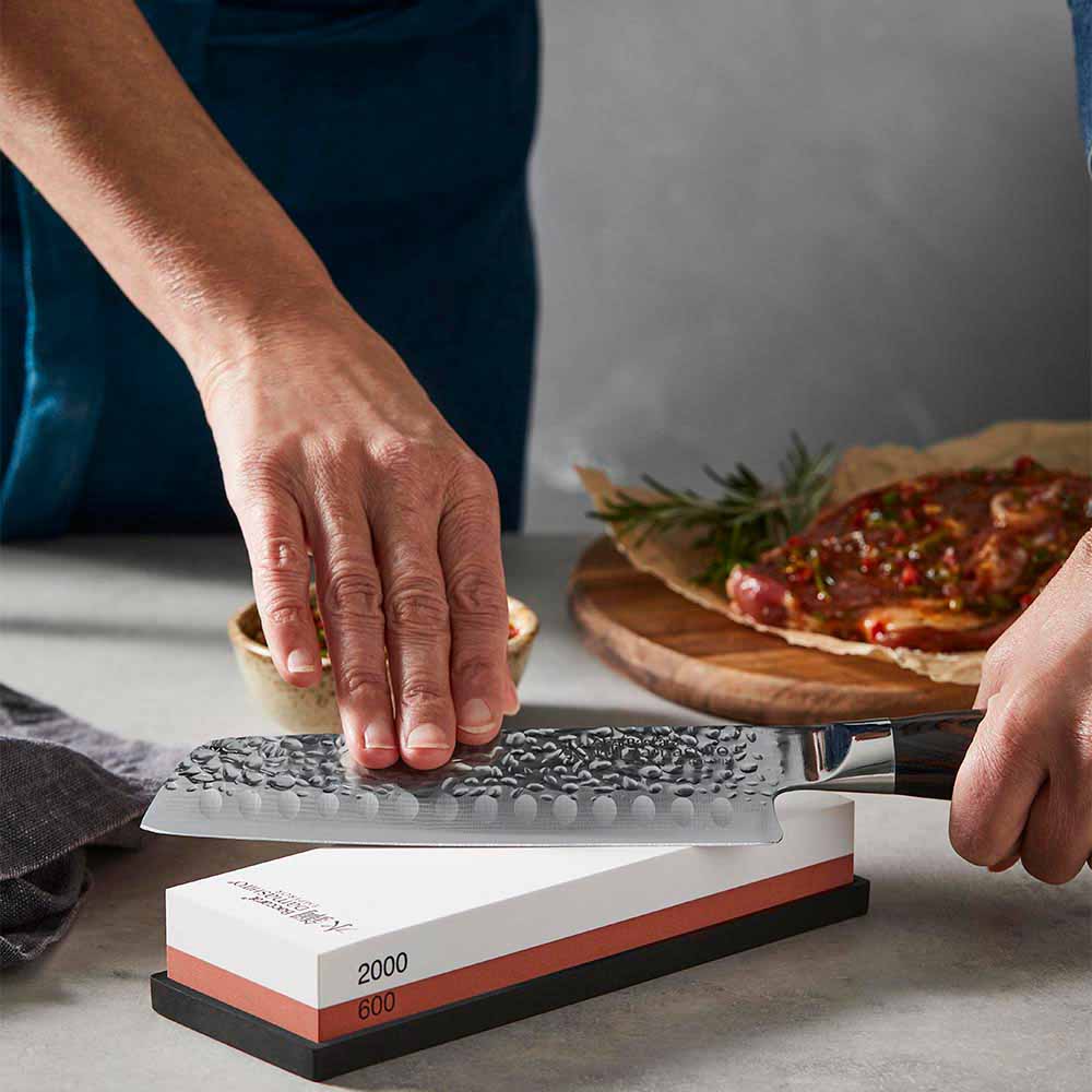woman sharpening knife using a whetstone - Baccarat