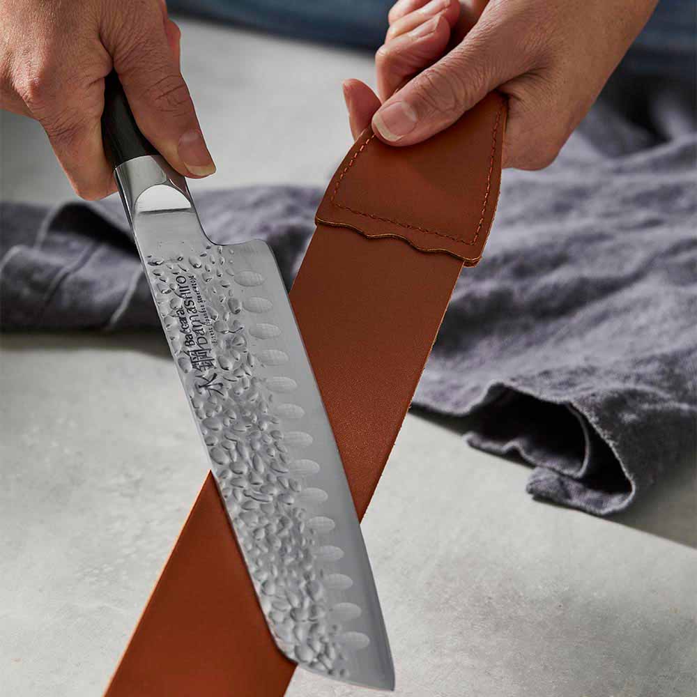 woman polishing knife with leather strop - Baccarat