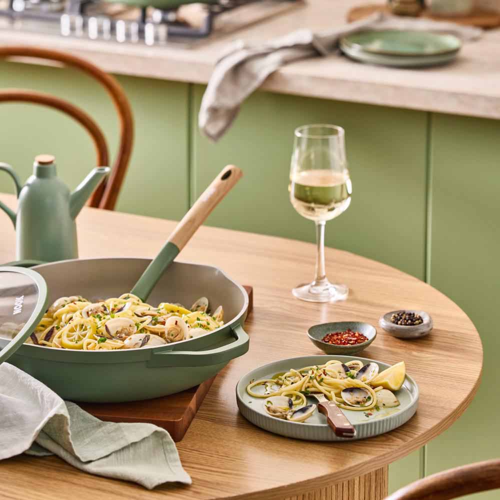 seafood pasta in a green saute pan with spouts