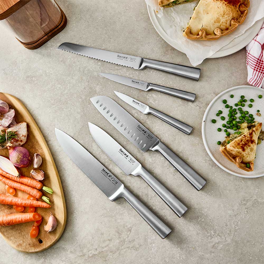 flat lay of kitchen knives surrounded  pie and vegetables