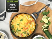 A black frying pan with vegetables and a fried egg hard anodised cookware 22cm fry pan - Baccarat